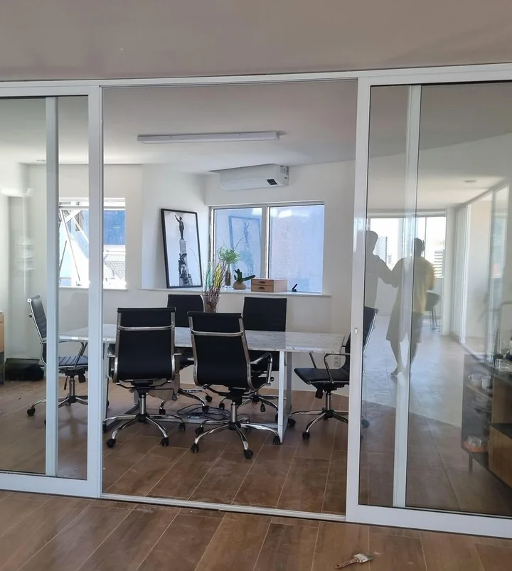 Divisória e porta de vidro com perfis brancos em ambiente de atendimento, do portfólio Audium
